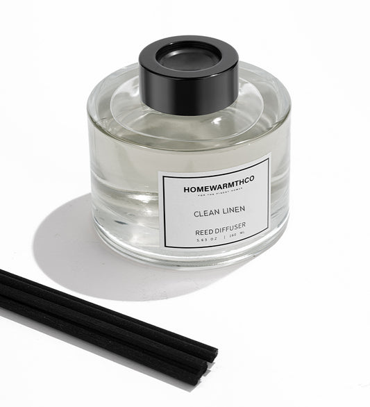 Homewarmthco Clean Linen reed diffuser with black cap and sticks on a white background