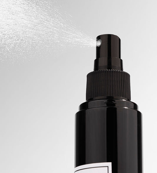 Black spray bottle with nozzle on a light gray background