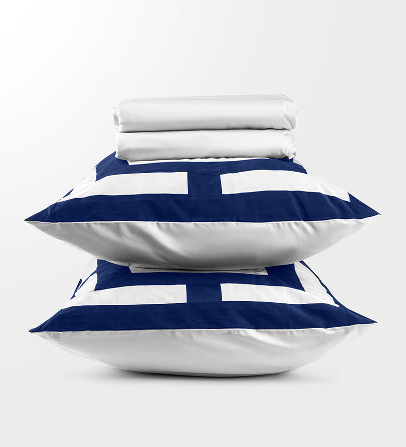 Stack of white bedding with blue and white striped pillows on a light gray background