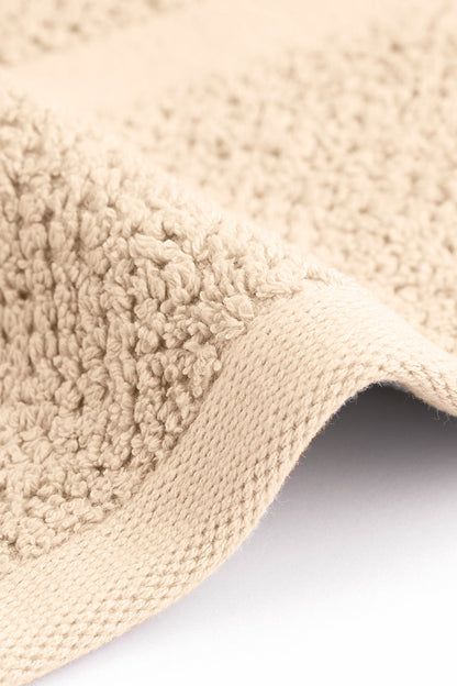 Close-up of a beige textured bath mat on a white background