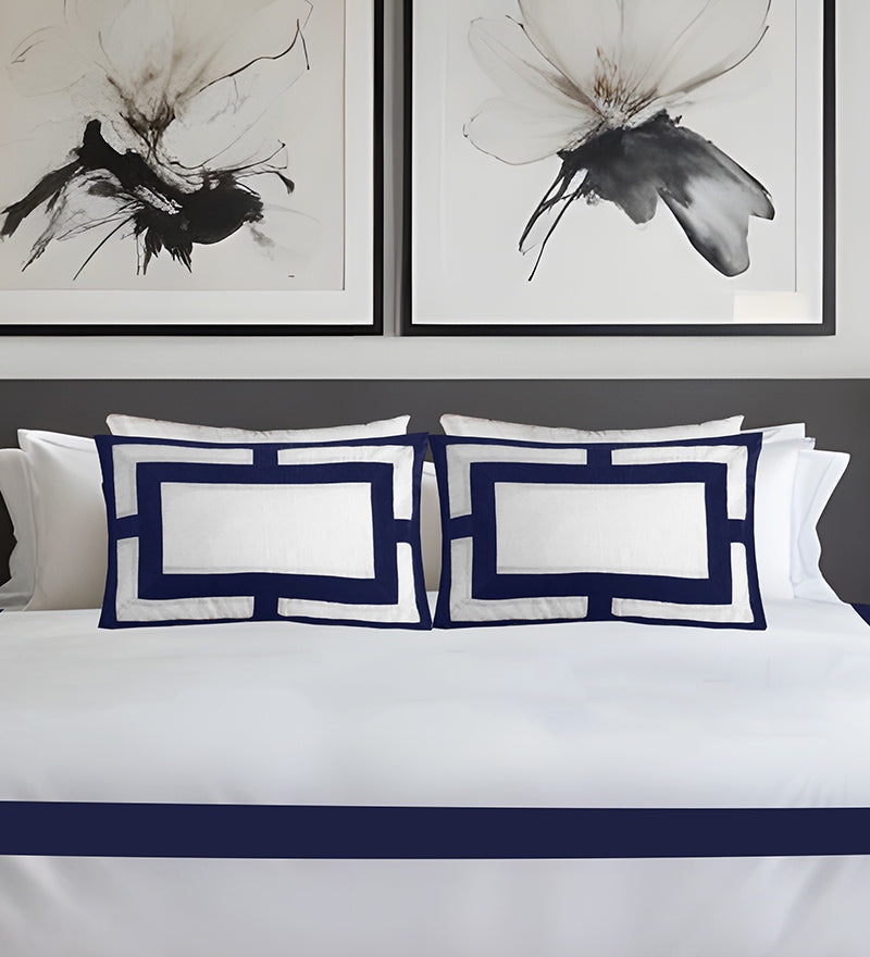 White bedding with navy blue accents and abstract butterfly artwork on the wall.