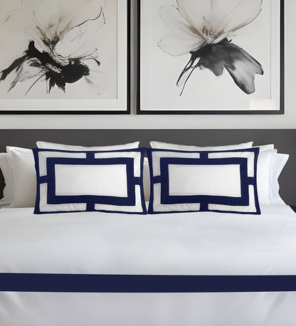 White bedding with navy blue accents and abstract butterfly artwork on the wall.