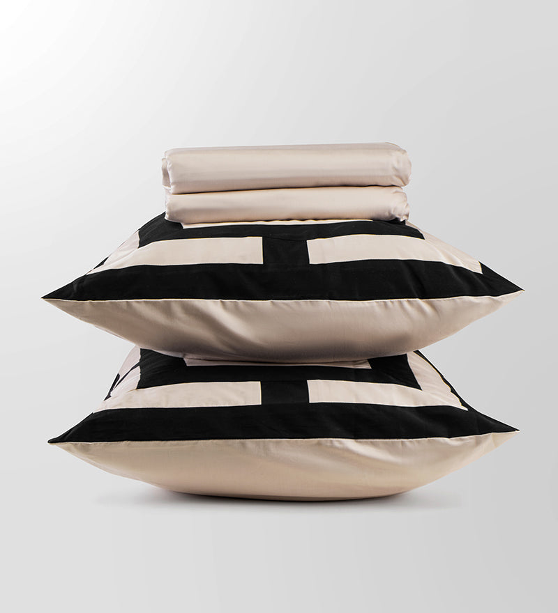 Stack of pillows with black and white geometric pattern on a light gray background