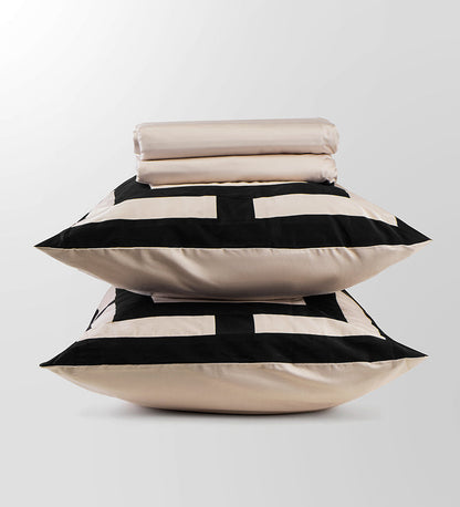 Stack of pillows with black and white geometric pattern on a light gray background