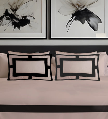 Decorative pillows with geometric patterns on a sofa, framed black and white artworks above.