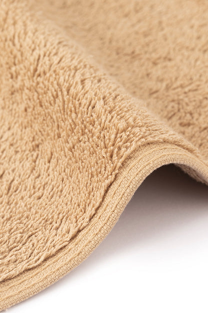 Close-up of a beige textured rug corner on a white background