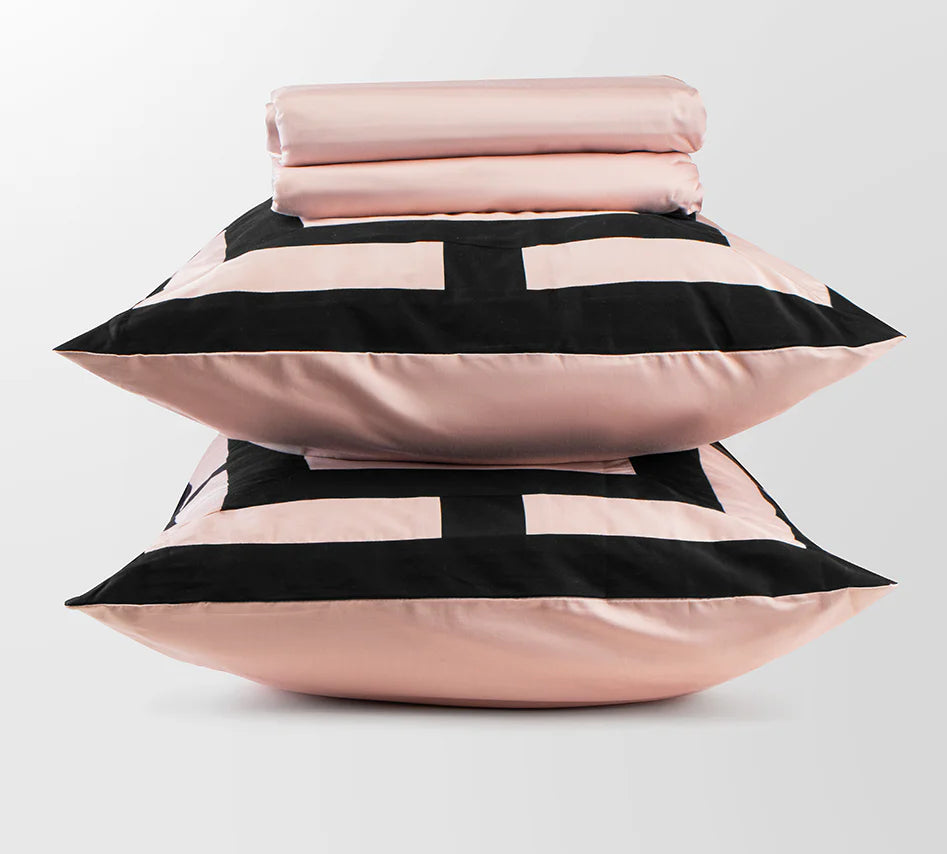 Stack of pink pillows with black stripes on a light gray background