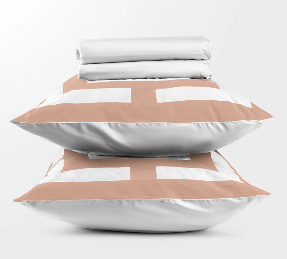 Stack of folded bed sheets and pillows on a light gray background