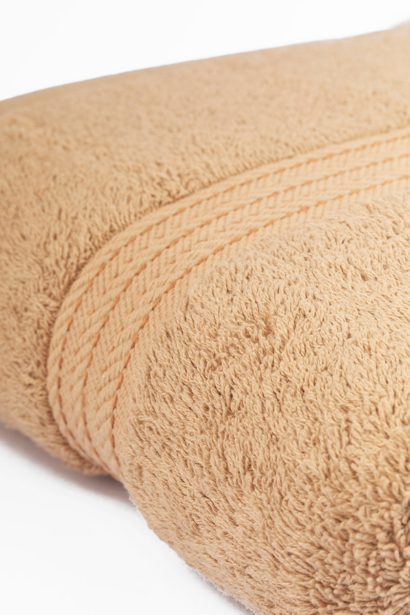 Close-up of a beige towel with visible texture and stitching on a white background