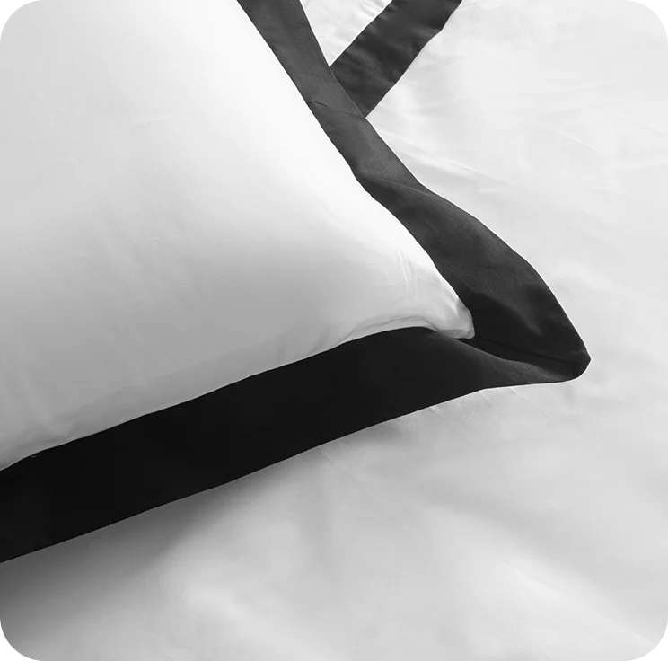 White pillow with black satin trim on a white background