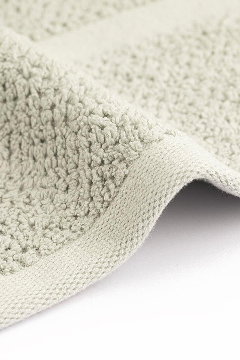 Close-up of a textured green rug corner on a white background