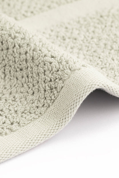 Close-up of a textured green rug corner on a white background