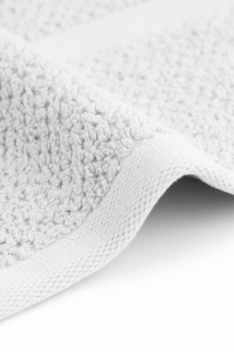 Close-up of a textured gray rug corner on a white background
