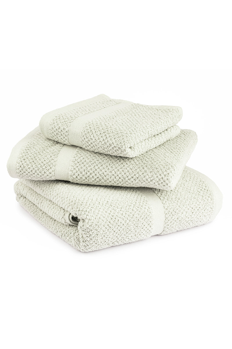 Set of three folded towels in light green on a white background