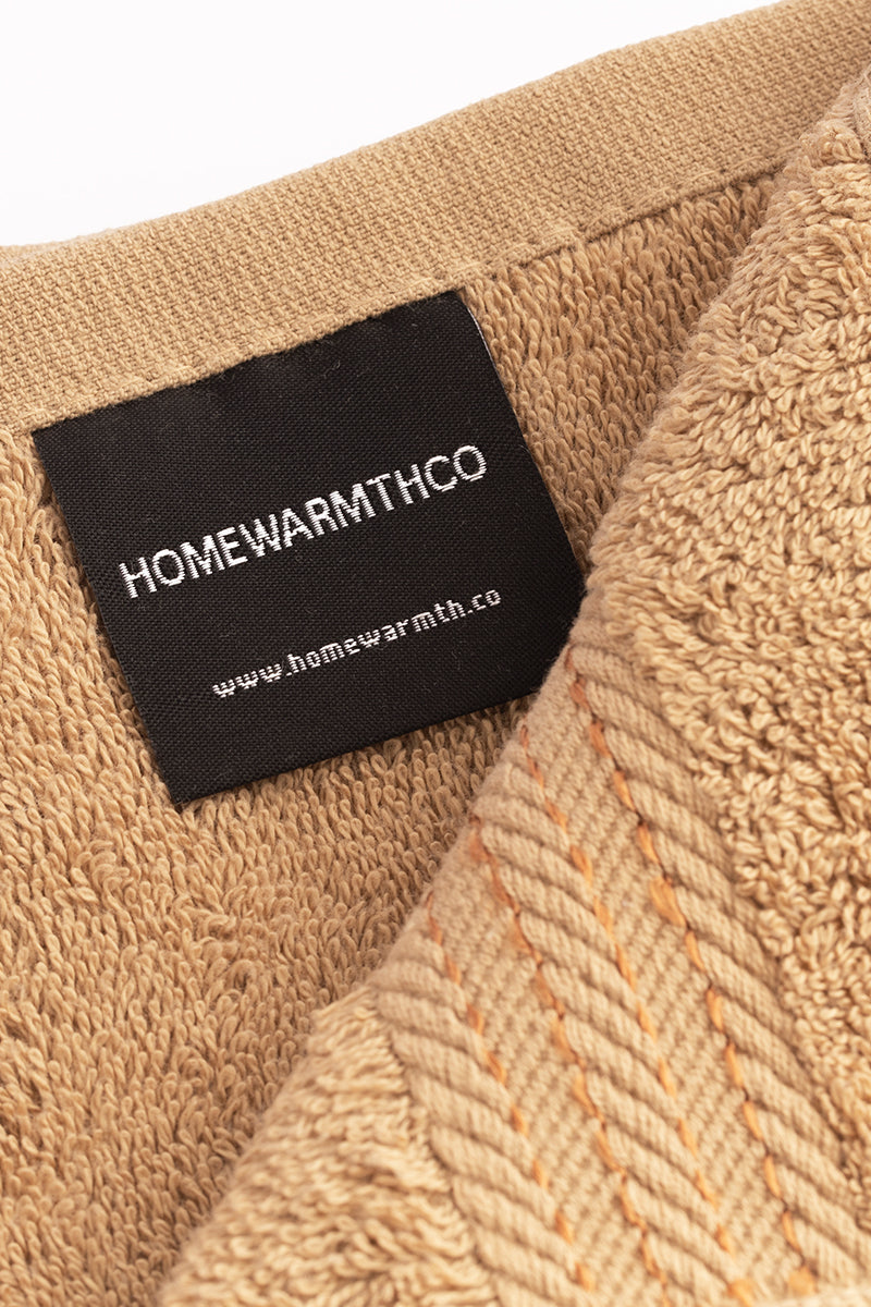 Close-up of a beige fabric with a black label displaying 'HOMEWARMTHCO' and a website URL.