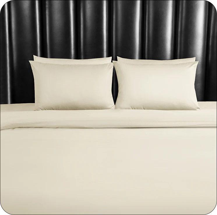 Beige bedding set with two pillows on a bed against a black headboard.