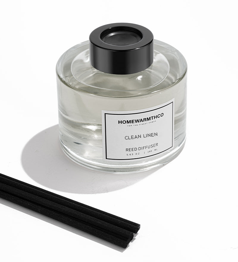 Homewarmthco Clean Linen reed diffuser with black cap and sticks on a white background