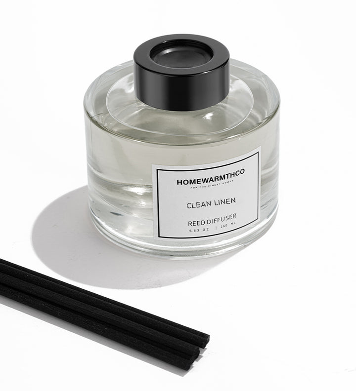 Homewarmthco Clean Linen reed diffuser with black cap and sticks on a white background