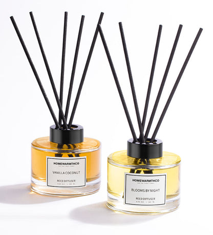 Two Homewarmthco reed diffusers with black sticks on a white background
