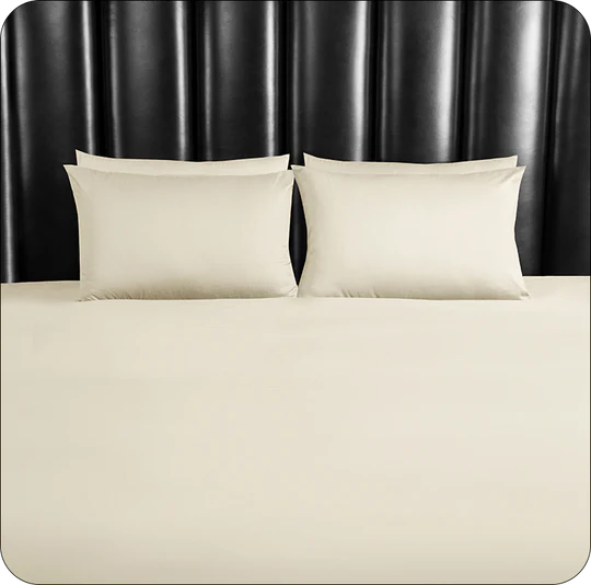 Beige bedding set with two pillows on a bed against a black headboard.