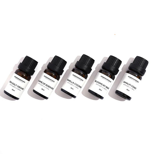 Set of six small essential oil bottles with black caps and white labels on a white background