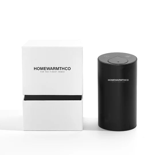 Black cylindrical electric diffuser with 'HOMEWARMTHCO' branding next to a white box on a white background