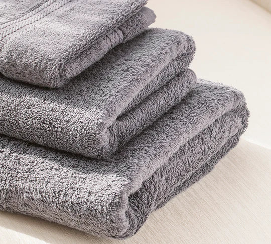 Stack of gray towels on a light wooden surface