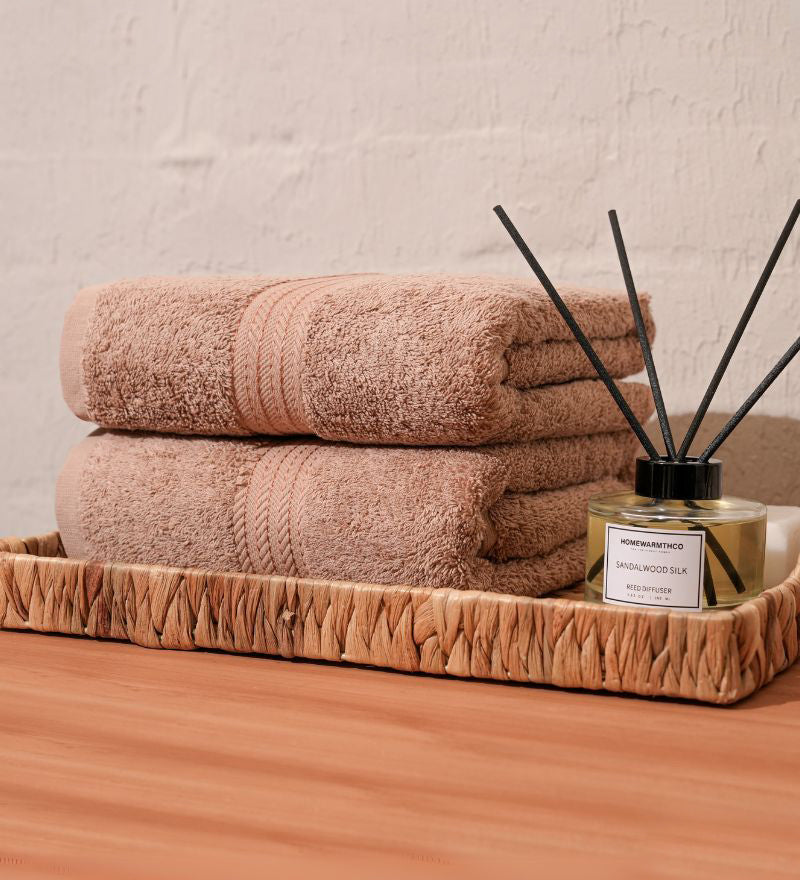 Stack of pink towels on a wooden tray with a diffuser in the background