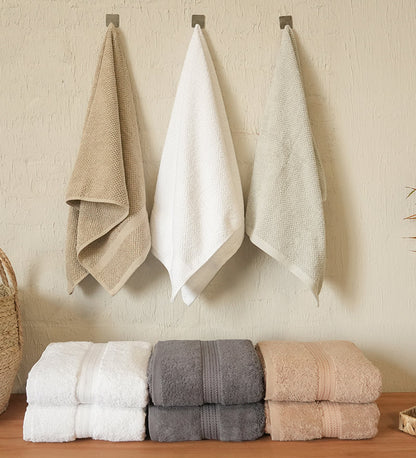 Set of folded and hanging towels on a wooden surface with a neutral wall background.