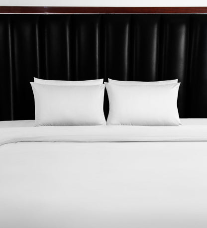 White pillows on a bed against a black headboard
