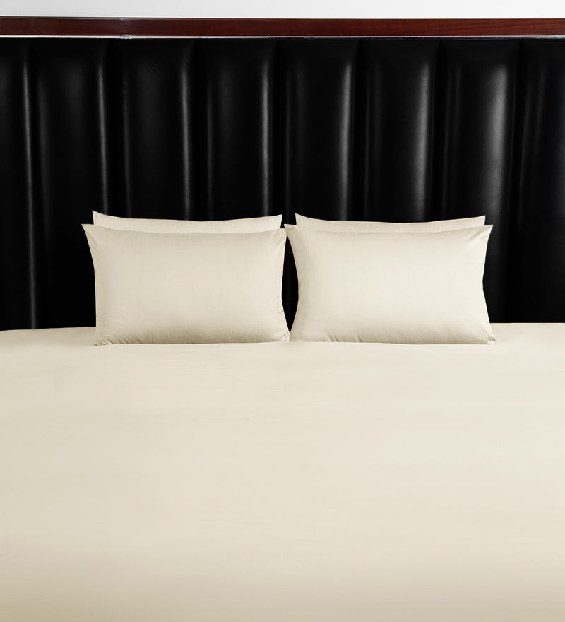 Two white pillows on a bed with a black headboard
