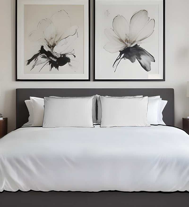 Bedroom with a bed featuring white bedding and pillows, and two framed black and white floral artworks on the wall.
