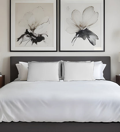 Bedroom with a bed featuring white bedding and pillows, and two framed black and white floral artworks on the wall.