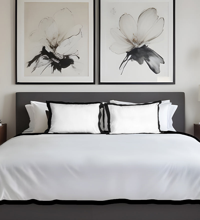 Bedroom with a bed featuring white bedding and black headboard, framed floral artworks on the wall.