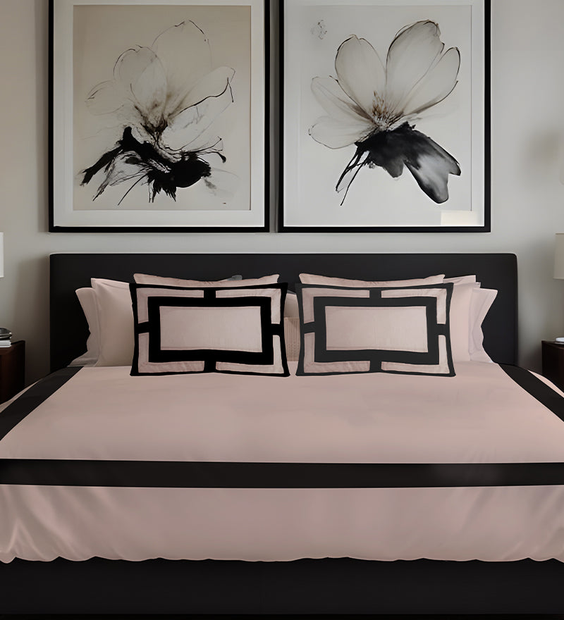 Bedroom with black and white floral artwork above a bed with matching pillows.