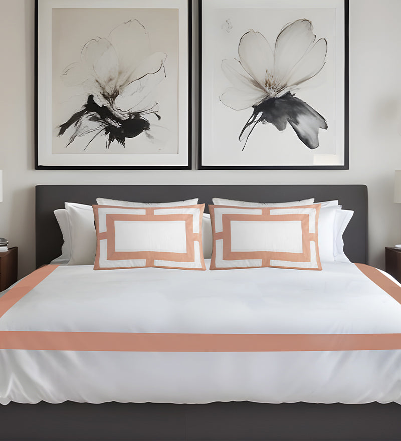 Bedroom with a bed featuring white bedding and peach-colored trim, two abstract flower artworks on the wall.