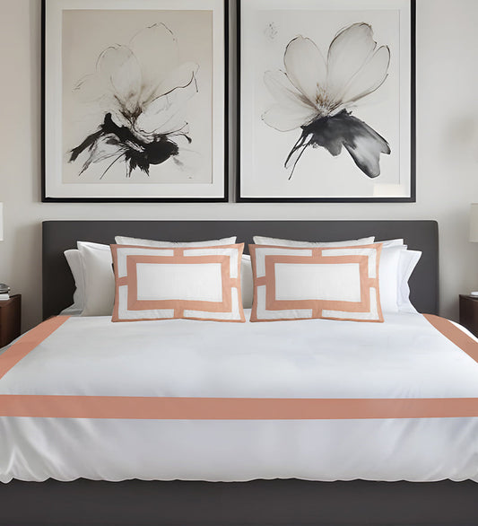 Bedroom with a bed featuring white bedding and peach-colored trim, two abstract flower artworks on the wall.
