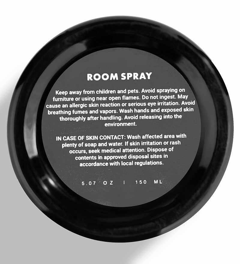 Black room spray container with safety information label on a white background