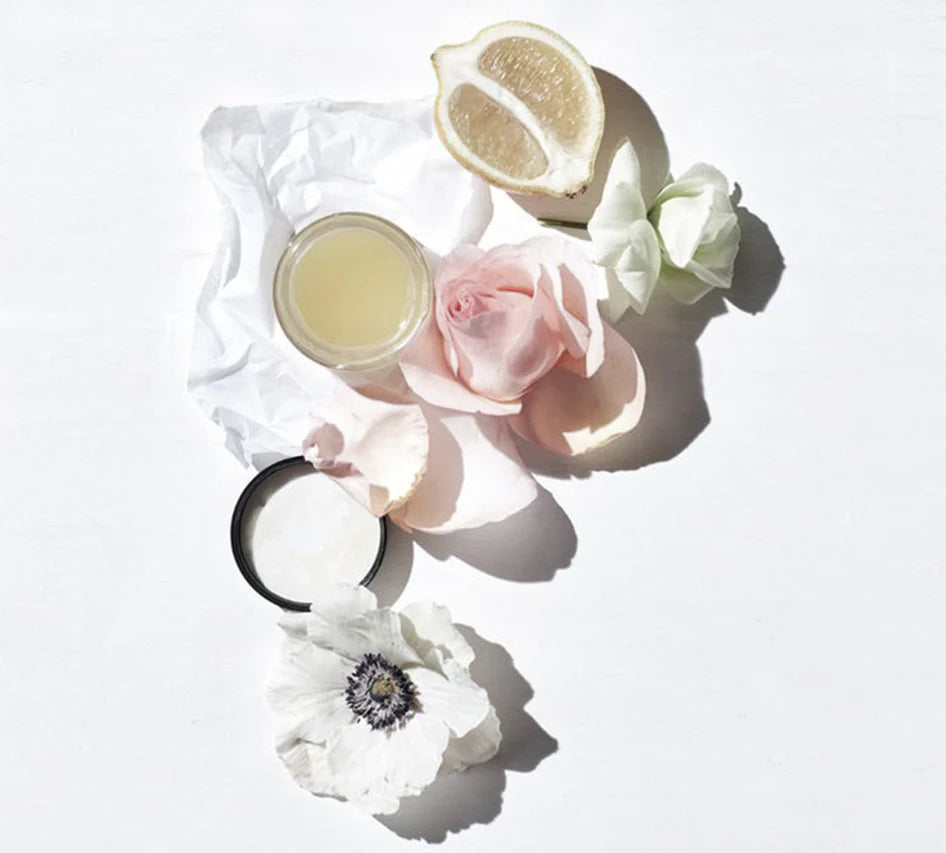 Gift box, two containers of cream or butter with a lemon and flowers on a white background