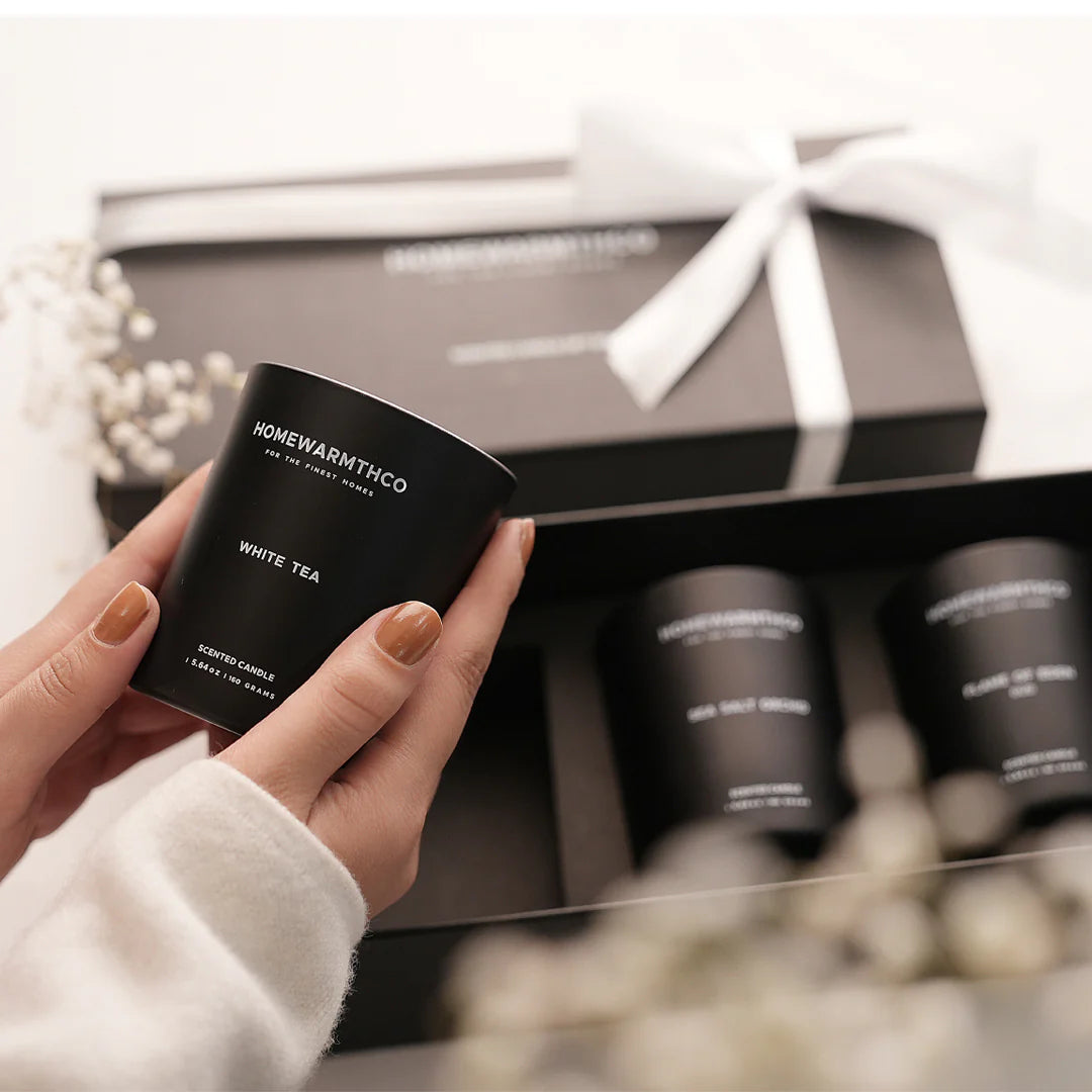 A girl holding a black container labelled 'HomeWarmthCo' with a gift box in the background.