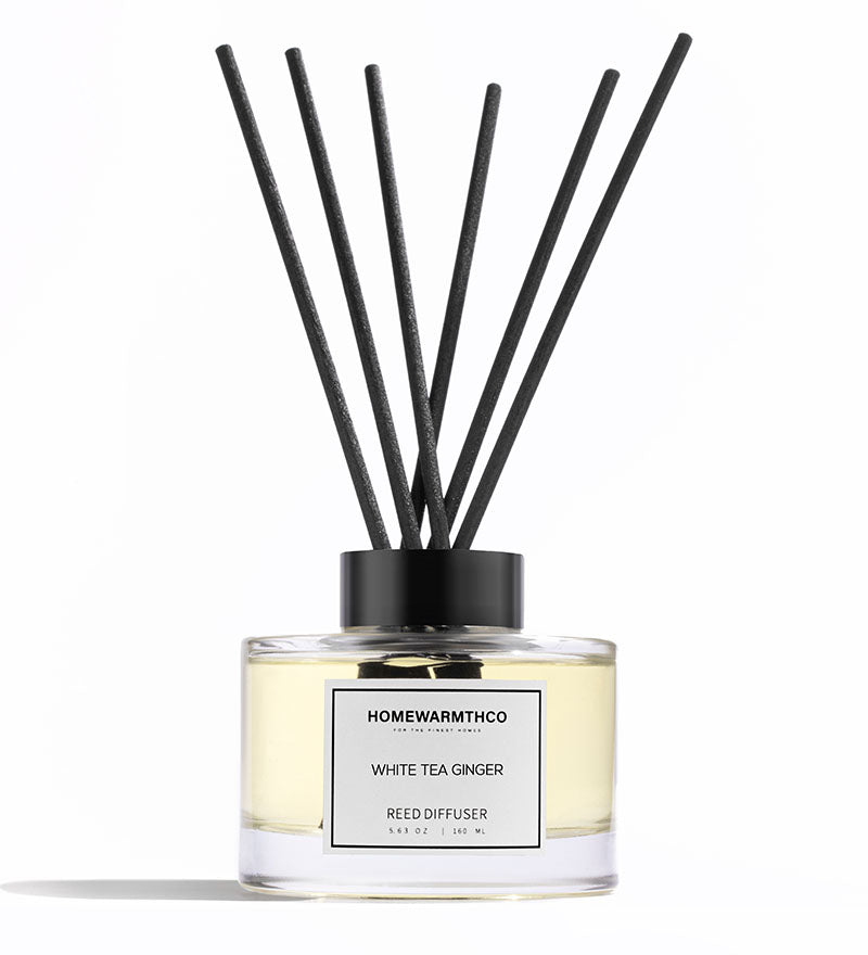 Reed diffuser with black sticks and a visible label on a white background